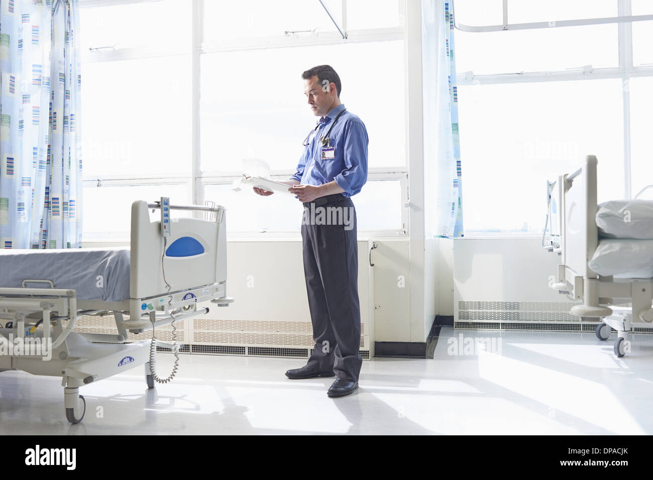 Arzt auf Krankenstation Blick auf medizinische Aufzeichnungen Stockfoto