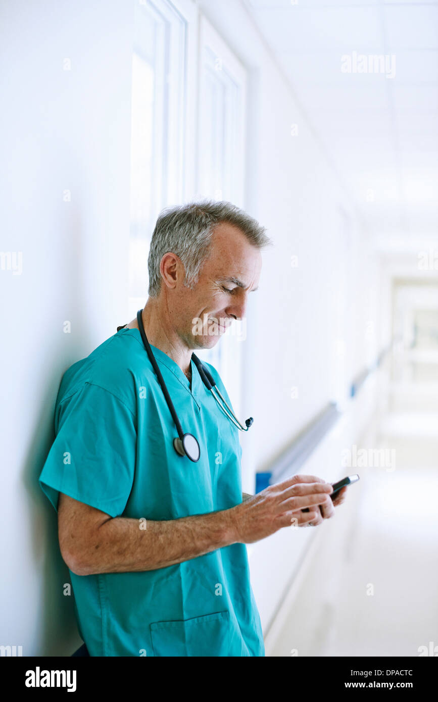 Chirurg im Korridor Smartphone betrachten Stockfoto