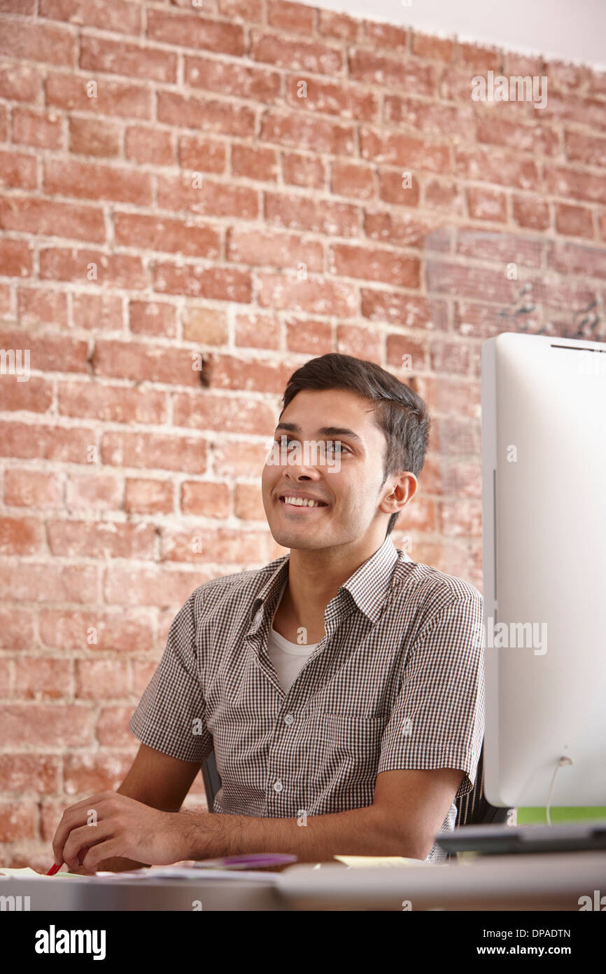 Porträt des jungen Mann am Schreibtisch mit Ziegelmauer Stockfoto