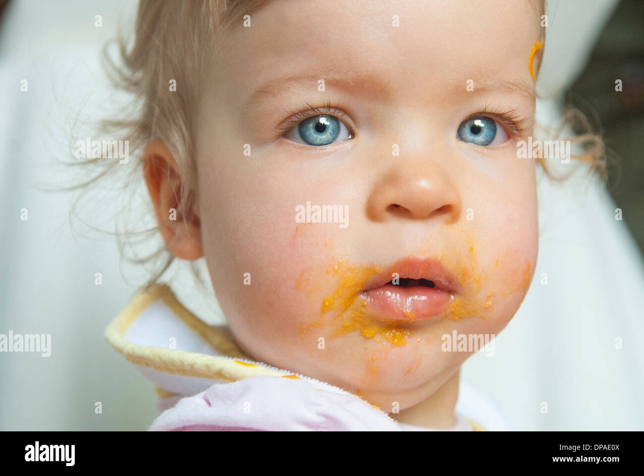 Babymädchen mit Essen im Mund Stockfoto