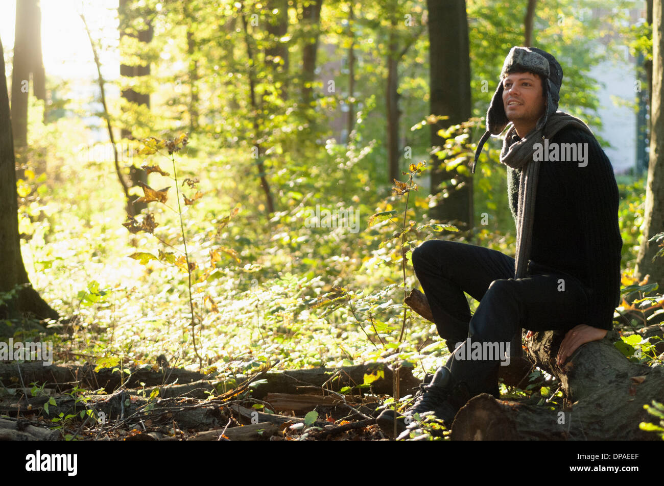 Porträt von Mitte erwachsenen Mann sitzt auf Log in Wald Stockfoto