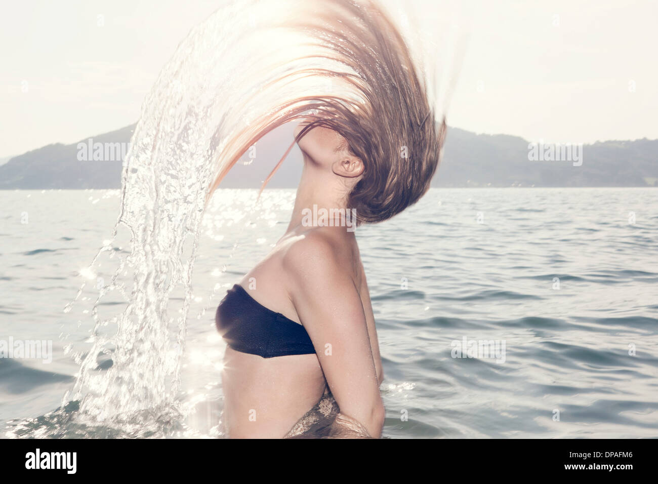 Junge Frau im Meer warf Kopf zurück Stockfoto