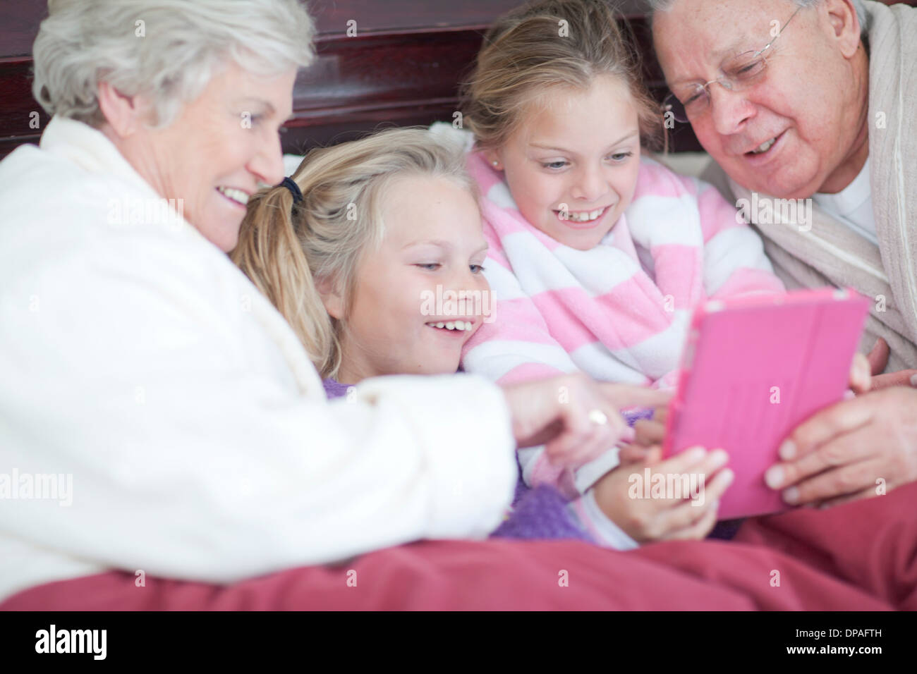 Großeltern und Enkelkinder digitale Spiel im Bett Stockfoto