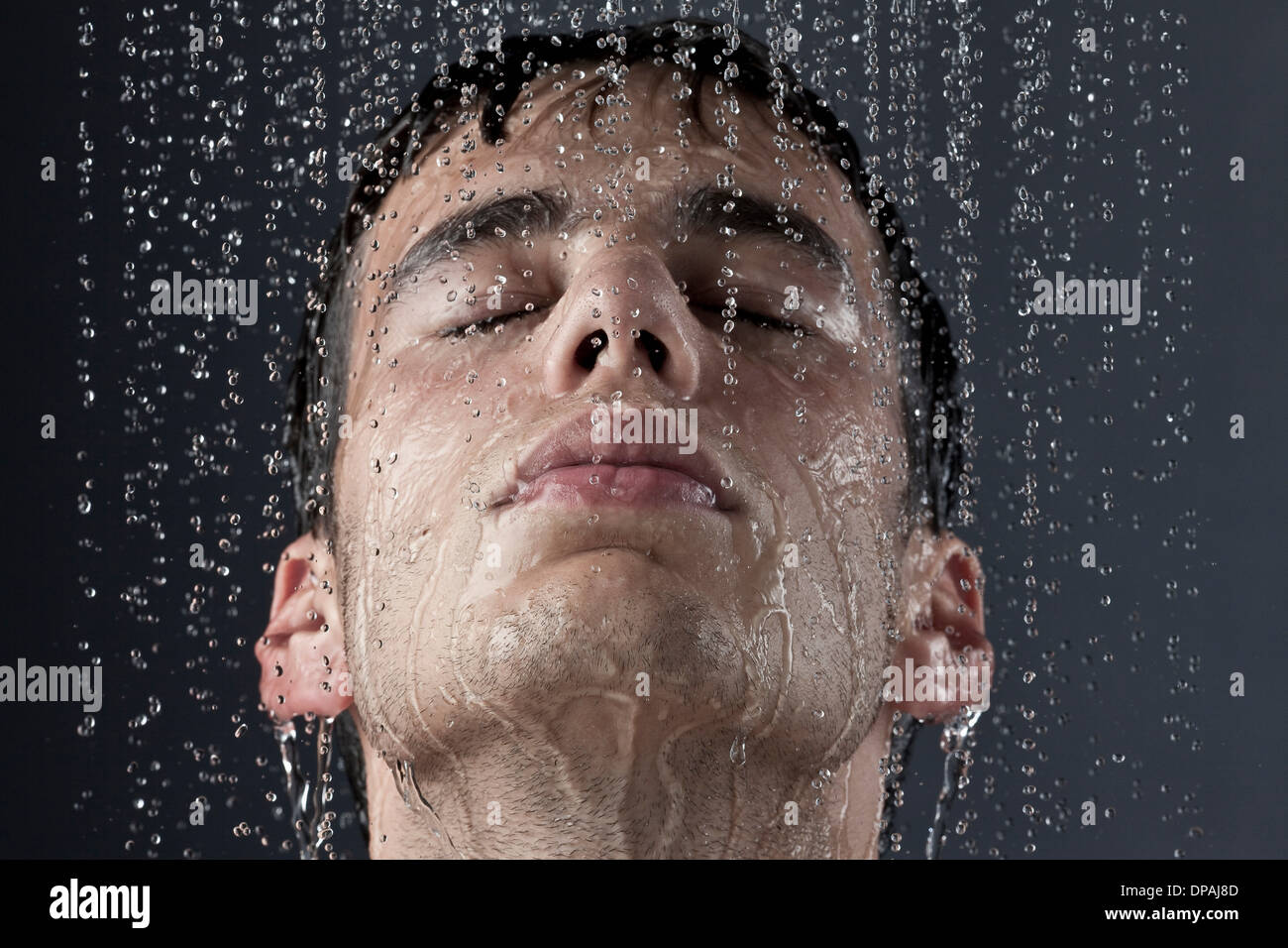 Junger Mann bedeckt mit Wassertröpfchen Stockfoto