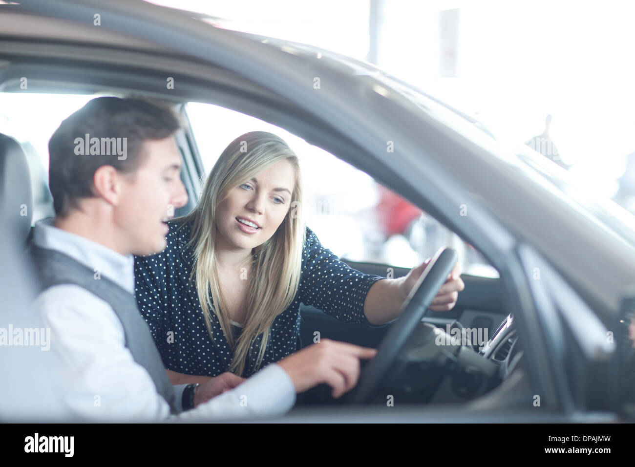 Auto Verkäufer beraten junge Frau im Autohaus Stockfoto