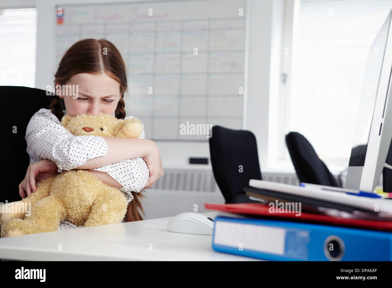 Mädchen sitzen im Büro umarmt Teddybär und Weinen Stockfoto
