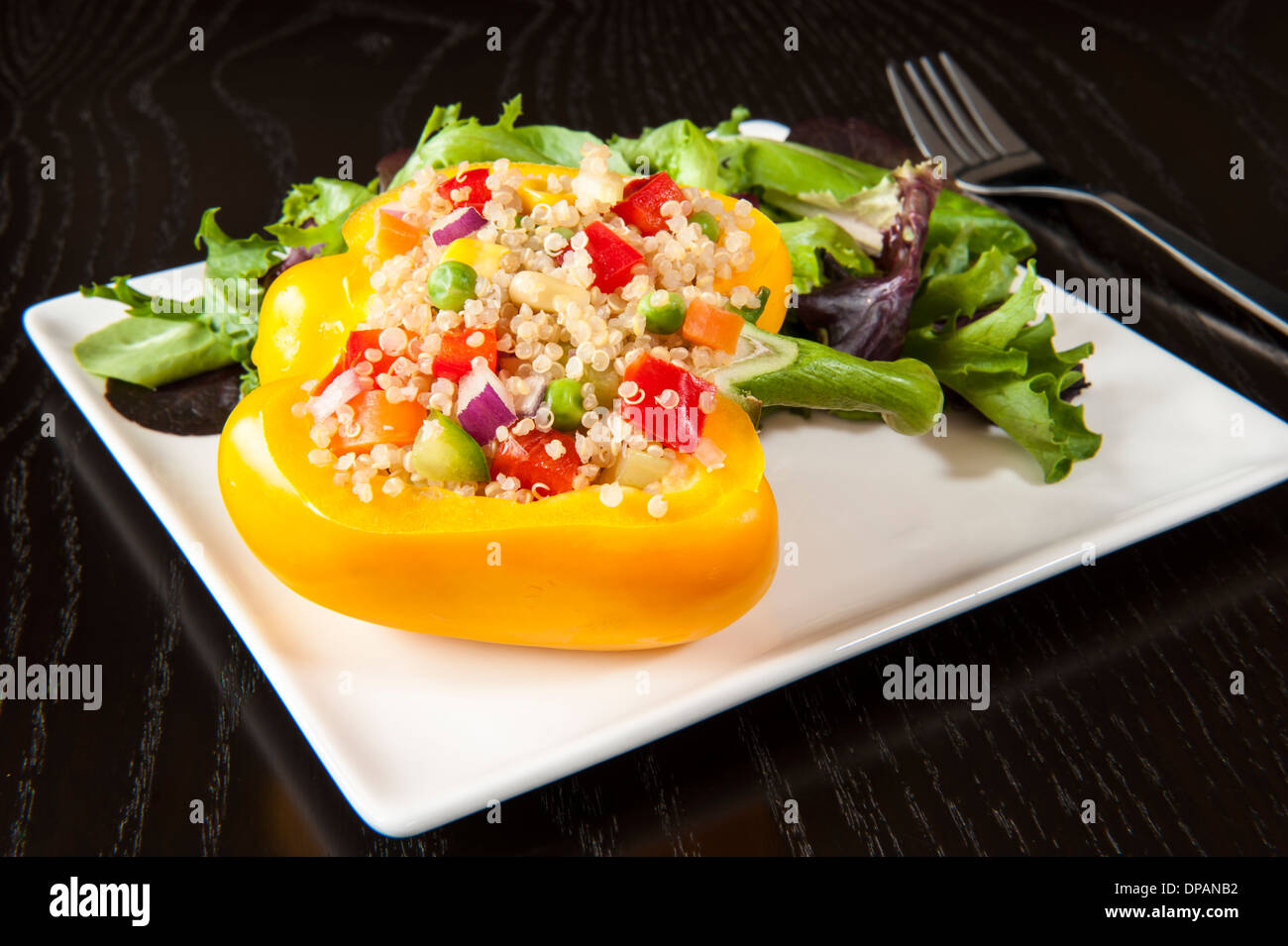 Quinoa gefüllte gelbe Paprika mit gemischten grünen Salat Stockfoto