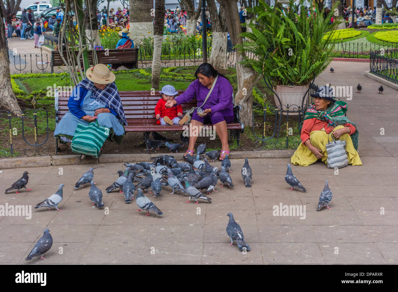 Drei Frauen und ein Baby, die füttert Tauben in der zentralen Plaza, Plaza 25 de Mayo, in Sucre, Bolivien. Stockfoto