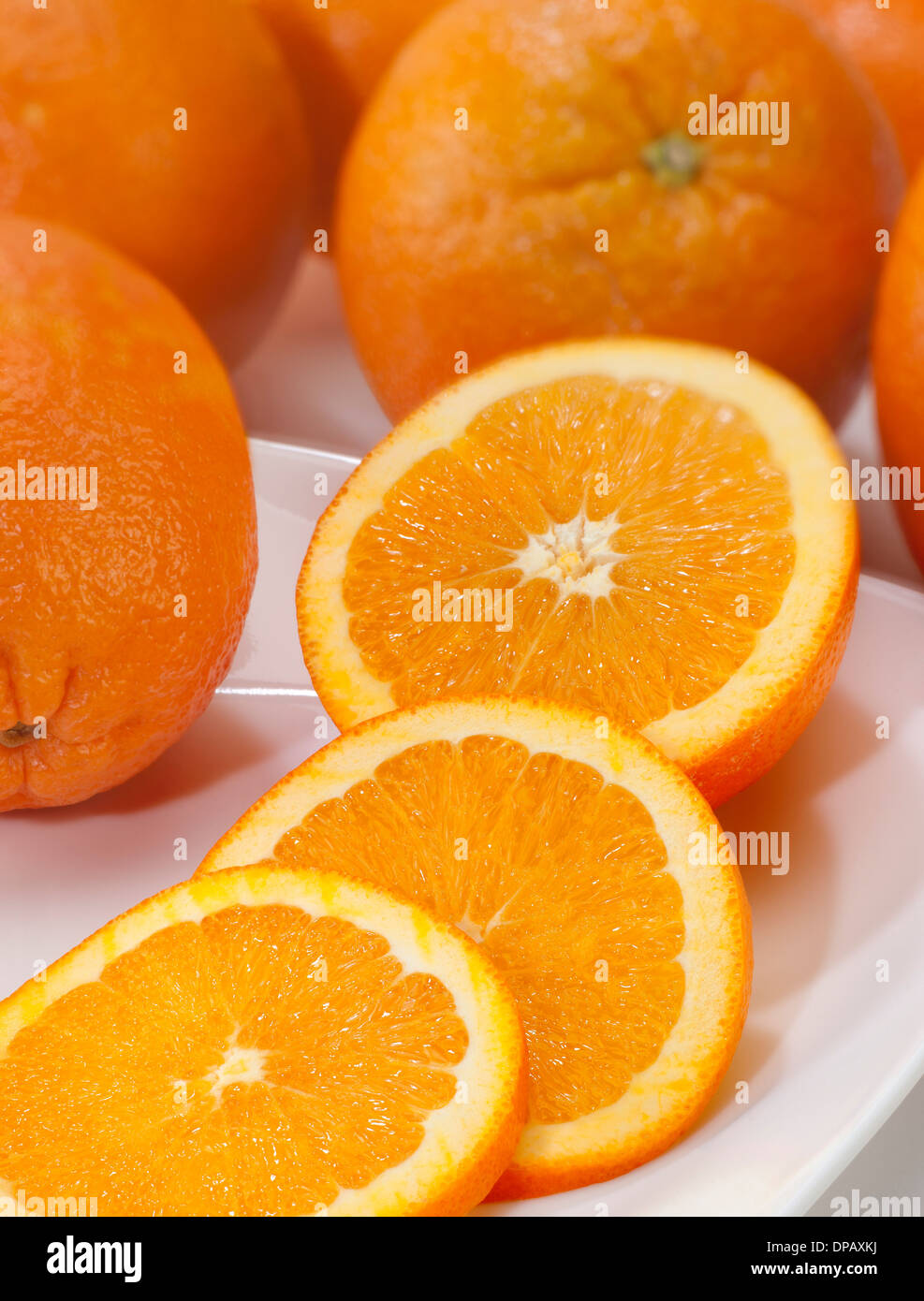 Orangen mit Scheiben auf einem weißen Teller Stockfoto