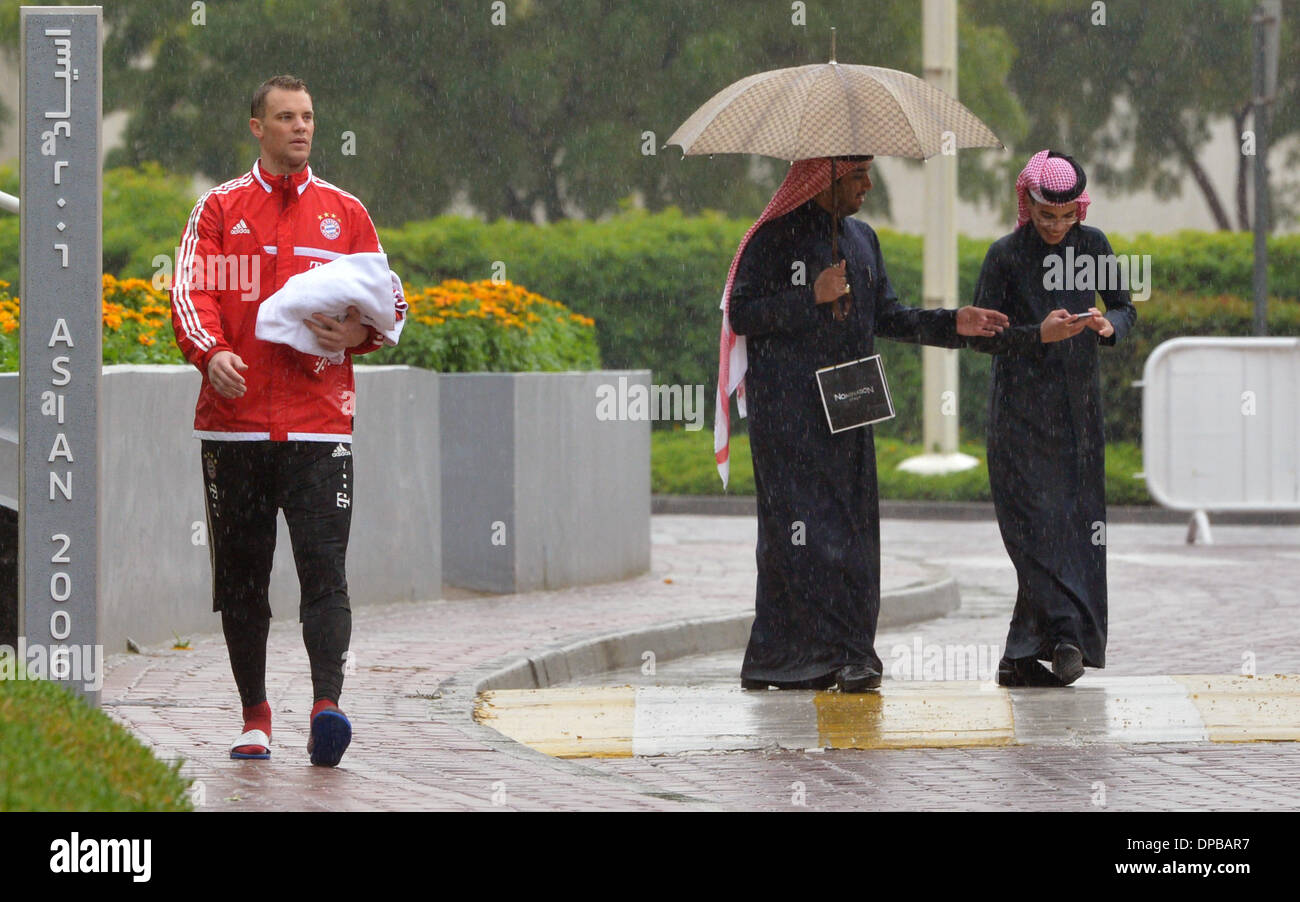 Doha, Katar. 11. Januar 2014. Bayern Torwart Manuel Neuer (L) geht aus dem  Gebiet der Berufsbildung im Team-Hotel in strömendem Regen in Doha, Katar,  11. Januar 2014. Auf der rechten Seite sind