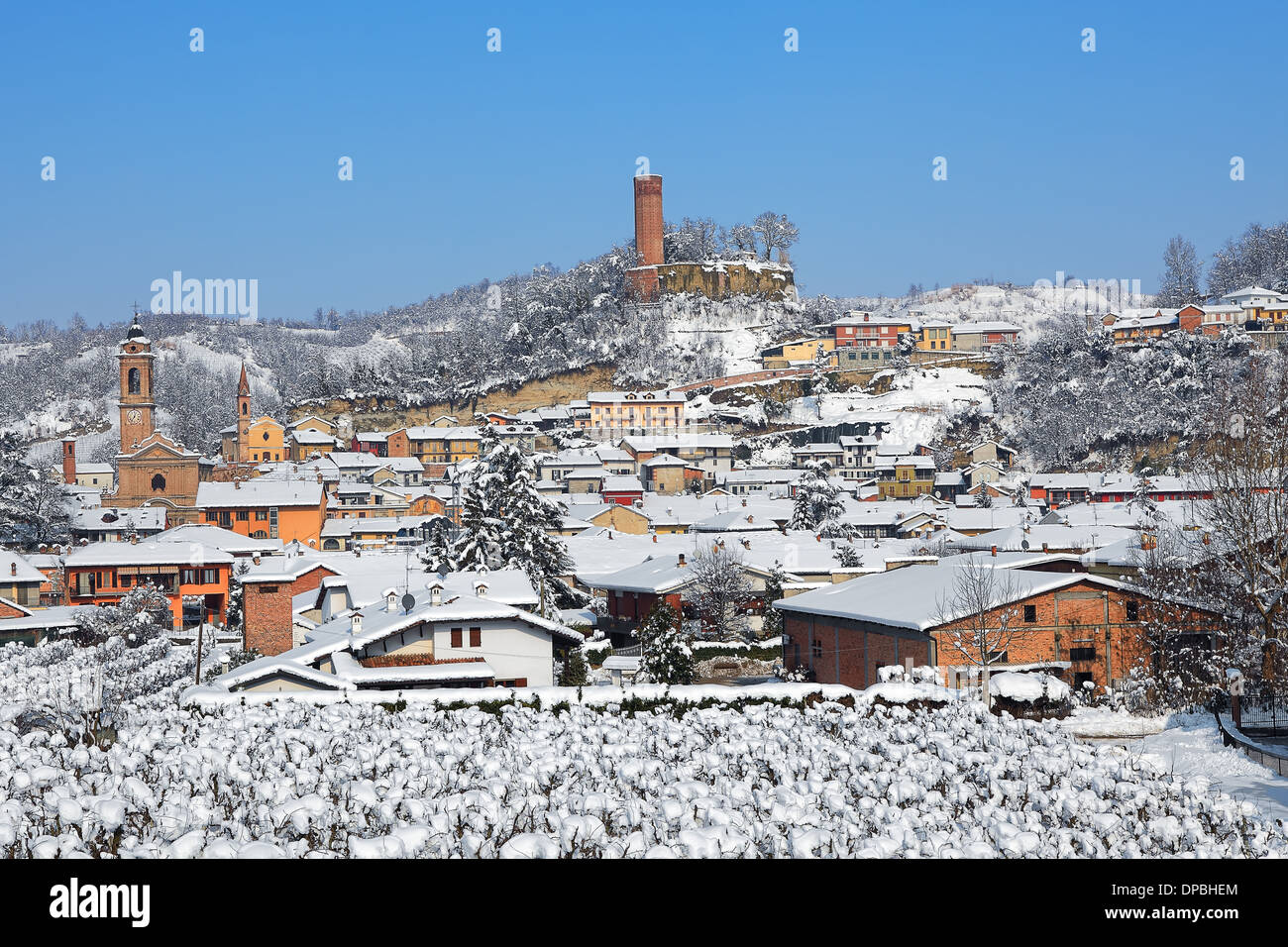 Ansicht der italienischen Kleinstadt bedeckt mit Schnee und mittelalterlichen Turm auf dem Hügel im Winter im Piemont, Norditalien. Stockfoto