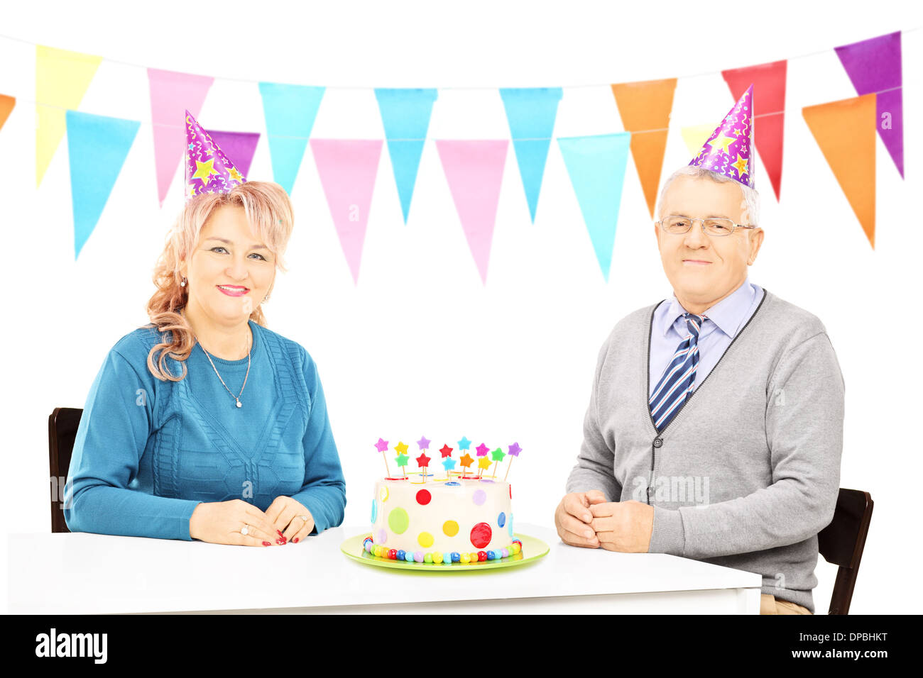 Älteres Paar sitzt am Tisch mit großen Kuchen und feiert Geburtstag Stockfoto