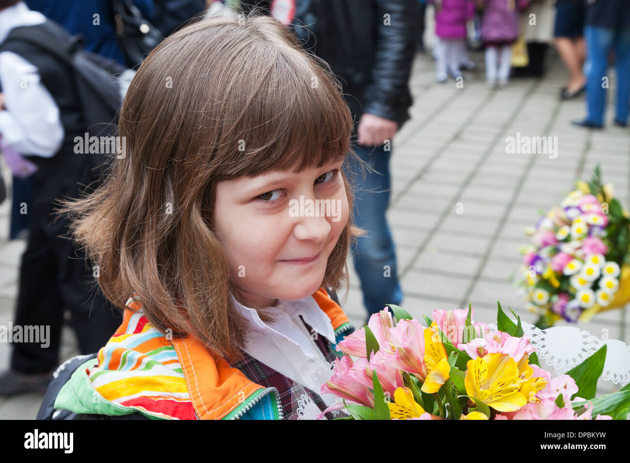 Schulmädchen mit Blumenstrauß geht in die Grundschule im Herbst Stockfoto