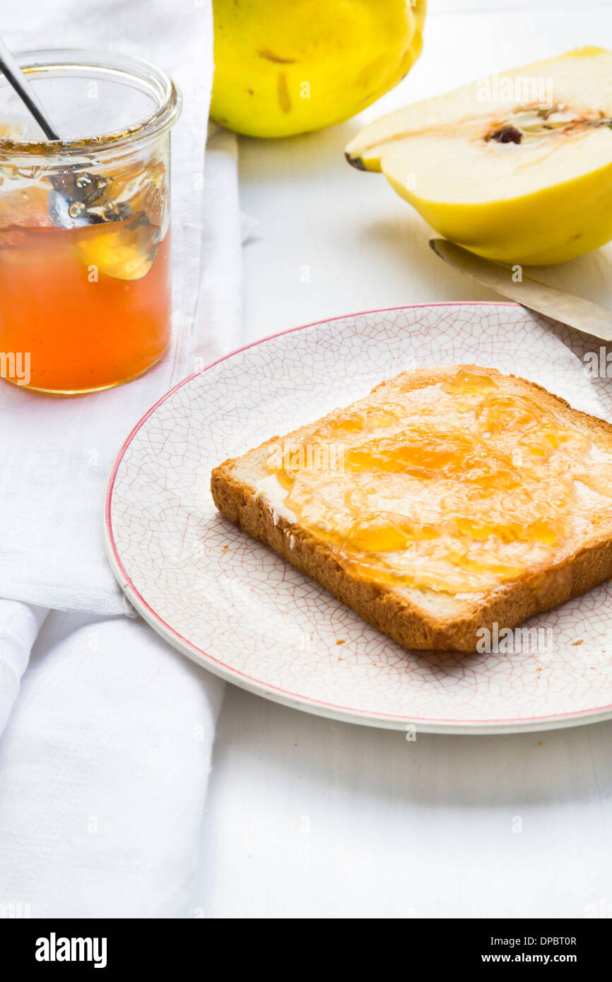 Quitte (Cydonia Oblonga), Selfmade Quittengelee und Scheibe Toast auf weißer Holztisch Stockfoto