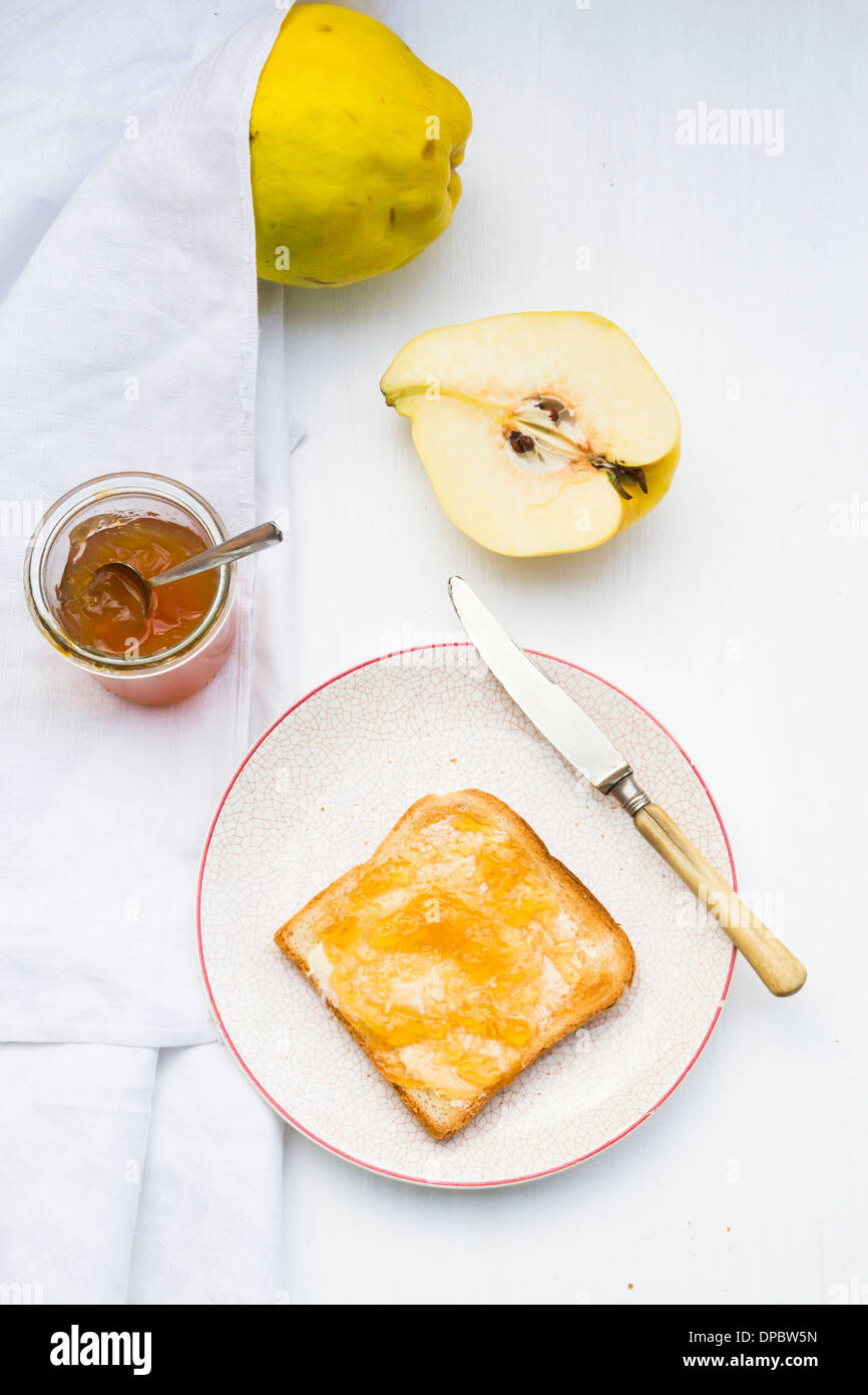 Quitte (Cydonia Oblonga), Selfmade Quittengelee und Scheibe Toast auf weißer Holztisch Stockfoto