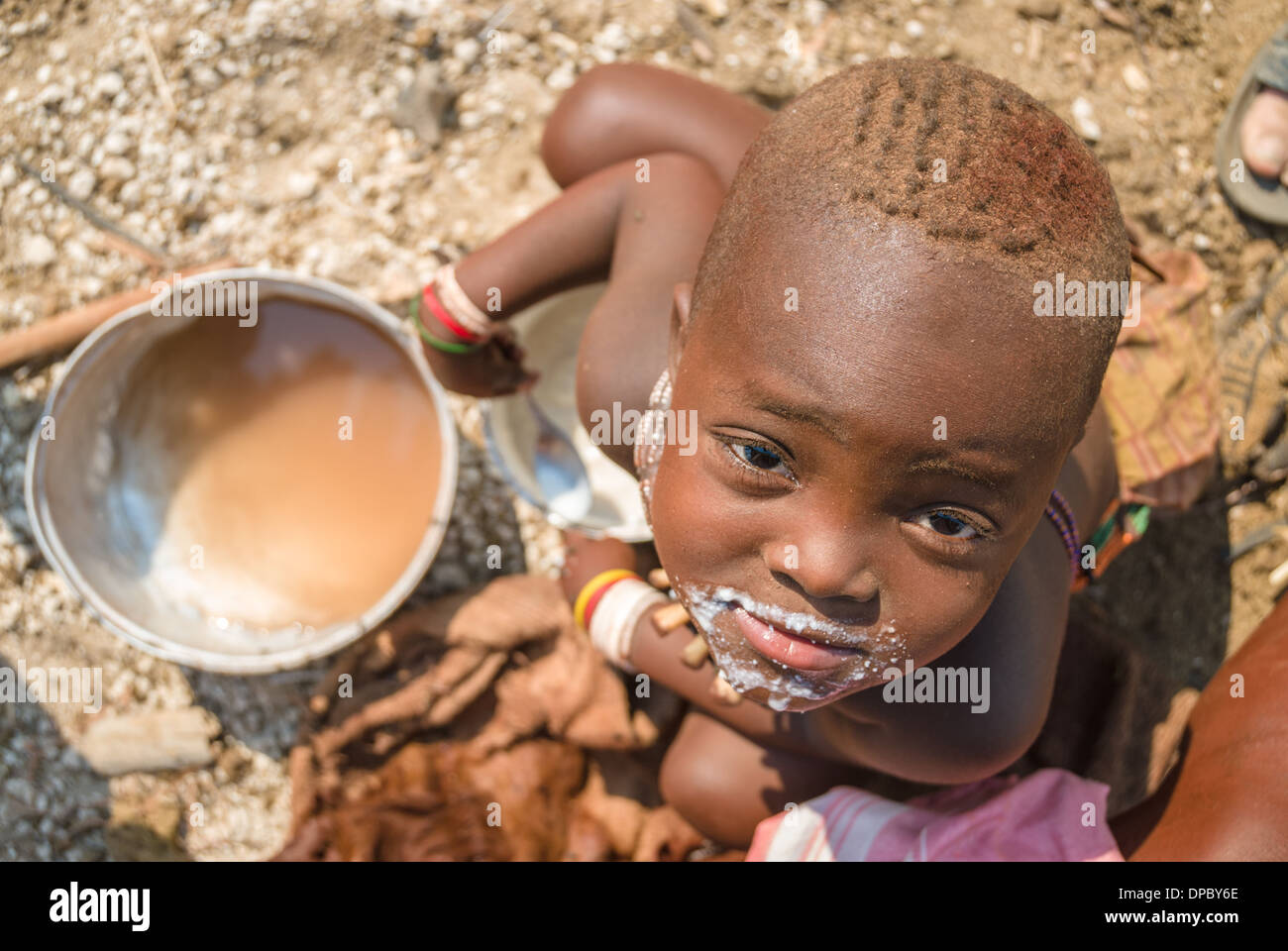 Junger Himba essen Brei aus einem Topf, Dorf in der Nähe von Epupa Wasserfälle, Kunene, Namibia, Afrika Stockfoto