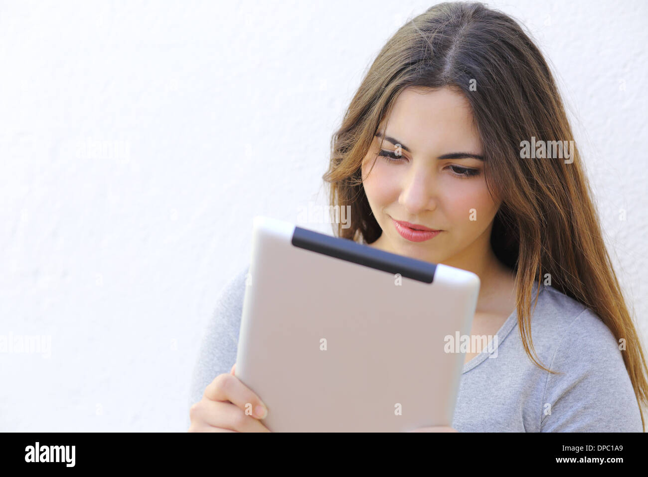 Porträt einer Frau, die eine Tablet Ebook auf einer weißen Wand lesen Stockfoto