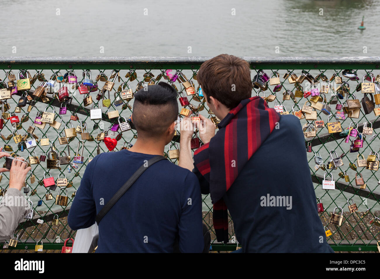 Paris. Frankreich. Zwei Jungs Haken ihre Vorhängeschloss auf dem Geländer der Brücke "Pont des Arts" Stockfoto