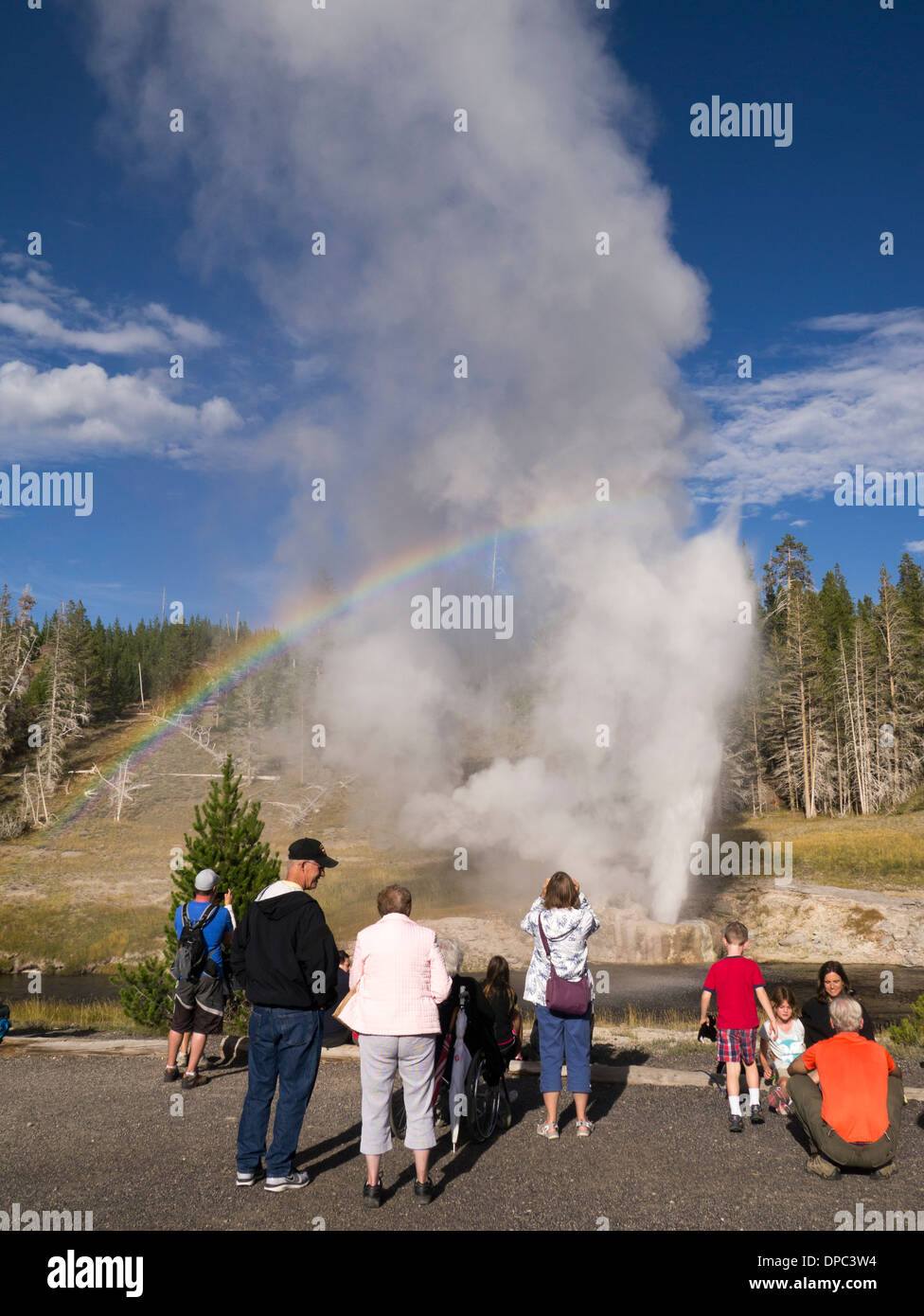 Touristen, die gerade des Ausbruchs des Riverside-Geysir im Yellowstone-Nationalpark, Wyoming, USA Stockfoto