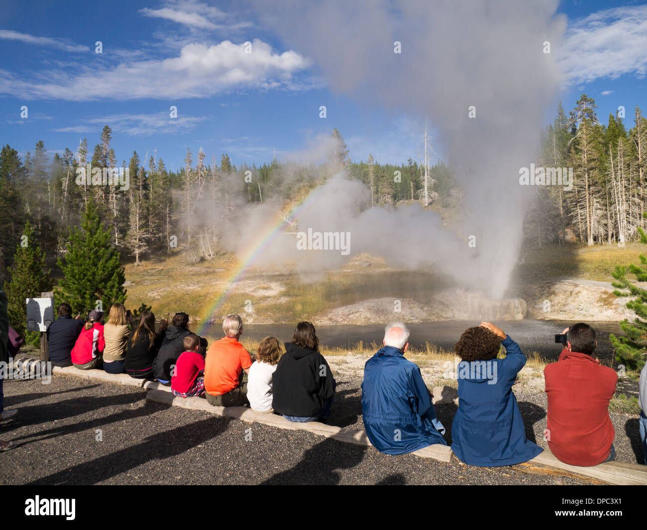 Touristen, die gerade des Ausbruchs des Riverside-Geysir im Yellowstone-Nationalpark, Wyoming, USA Stockfoto