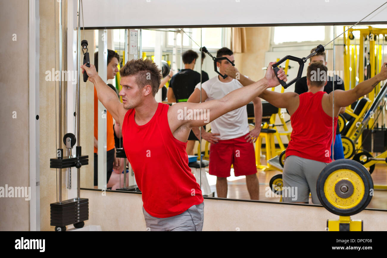 Junger Mann Training an Fitnessgeräten, ziehen der Griffe am Kabel Maschine Stockfoto
