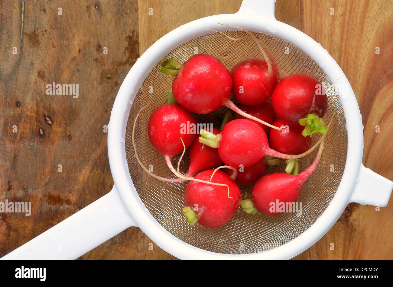 Radieschen in weißen Sieb auf rustikalen hölzernen Hintergrund mit Platz für Text gewaschen Stockfoto