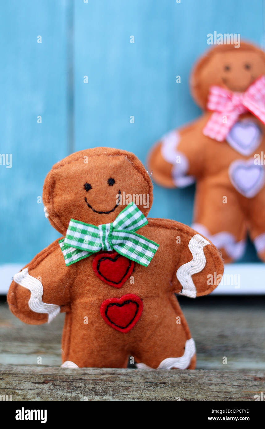Ein Spielzeug fühlte Gingerbread Man mit einer Schleife und Herz Tasten, einen zweiten in einer geringen Tiefenschärfe Hintergrund. Eine lustige Weihnachten oder Valentinstag Bild Stockfoto