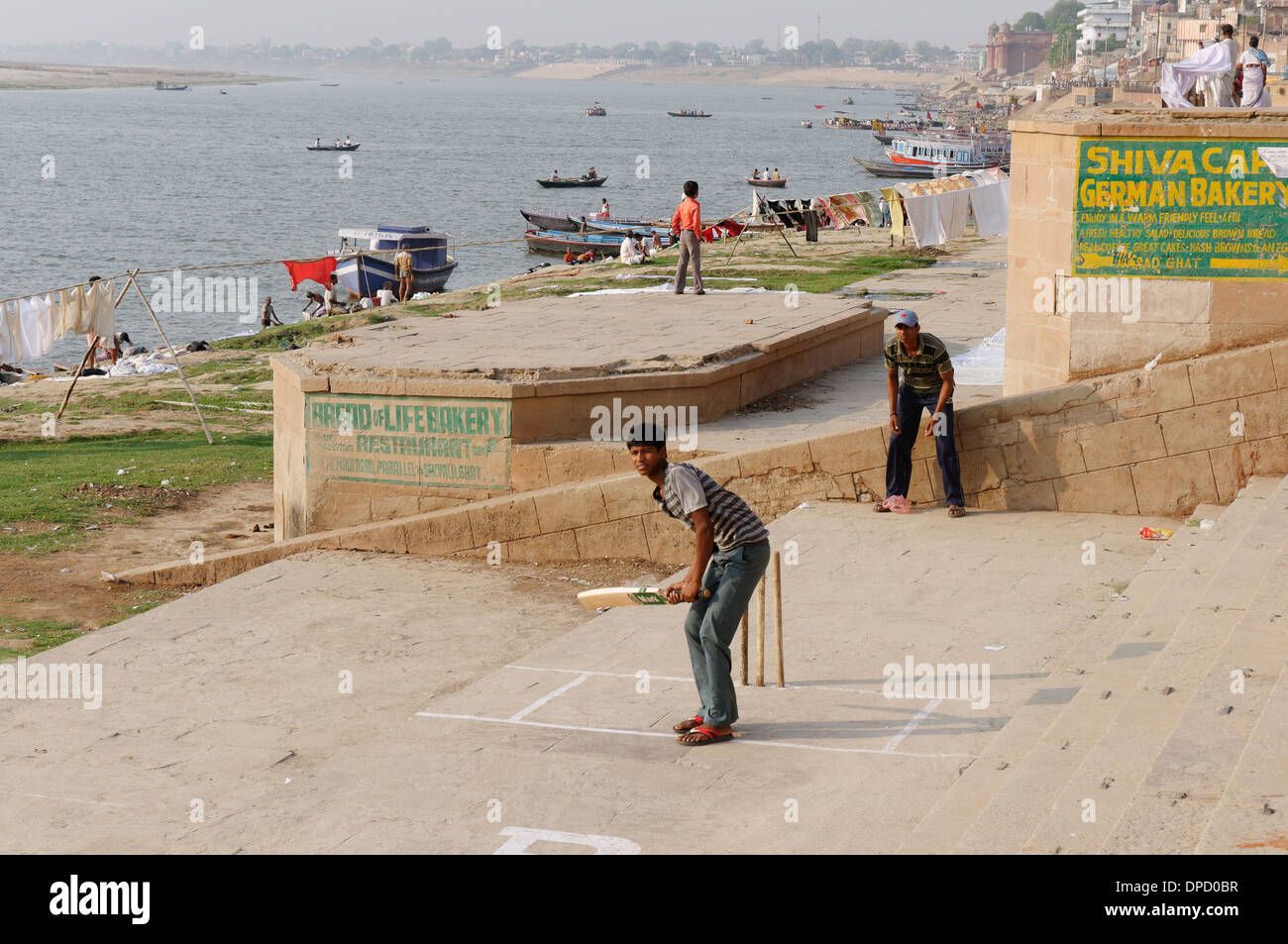 Junge Männer spielen Cricket auf den Ghats neben den Ganges in Varanasi Stockfoto