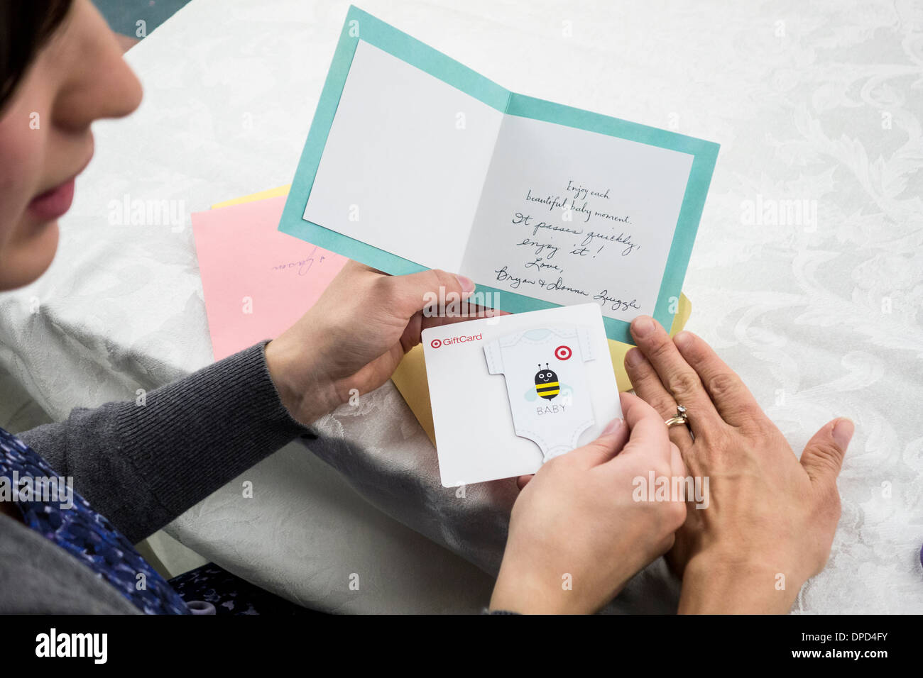 Eine werdende Mutter schaut sich eine Dusche Geschenkkarte mit ihrer Mutter. Nahaufnahme von Händen und Karte. USA. Stockfoto