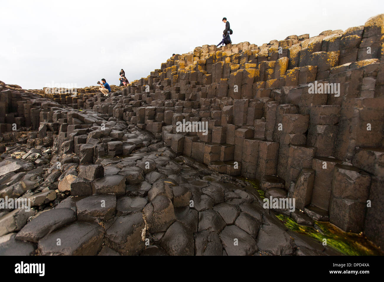 Besucher klettern und Klettern über die Basaltsäulen, aus denen sich die Welt berühmten Giants Causeway in der Grafschaft Antrim. Stockfoto