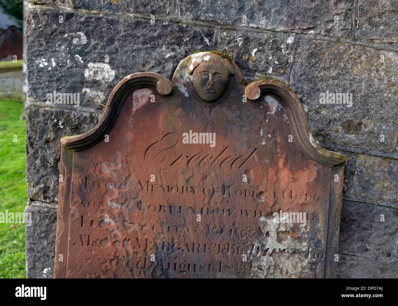 19.. Jahrhundert Grabstein mit menschlichem Antlitz Design. Kirche von St. Michael. Torpenhow, Cumbria, England, Vereinigtes Königreich, Europa. Stockfoto