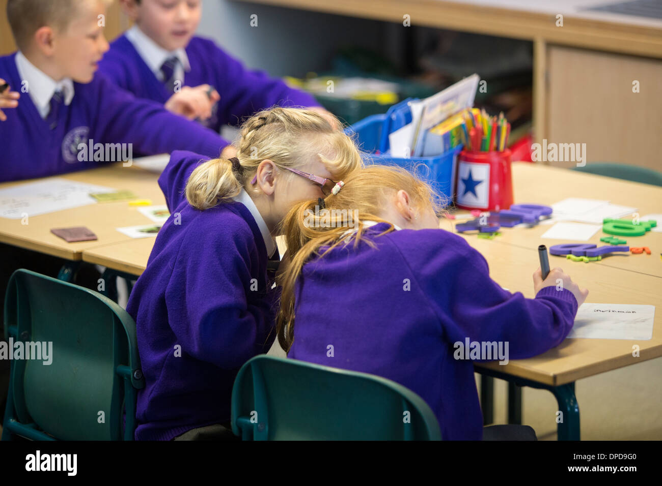 Zwei Freunde Flüstern in einer Grundschule Klasse Stockfoto