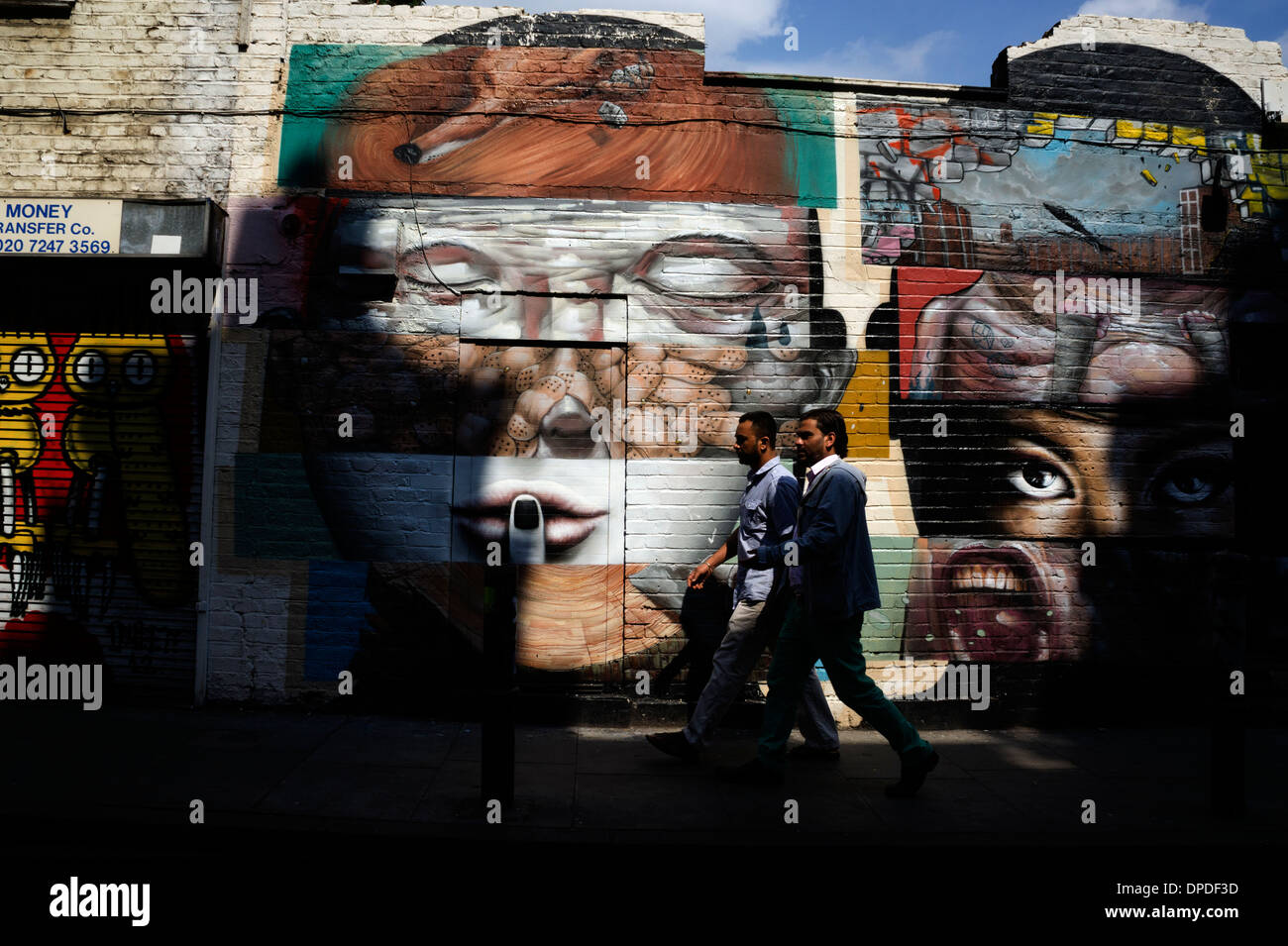 Zwei junge asiatische Männer vorbei an städtischen Spray können Graffiti Streetart Brick Lane Bereich, East London E1 UK Stockfoto