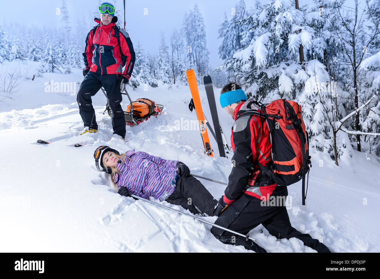 Ski Patrol Hilfe verletzte Frau Skifahrer im Schnee liegend zu retten Stockfoto