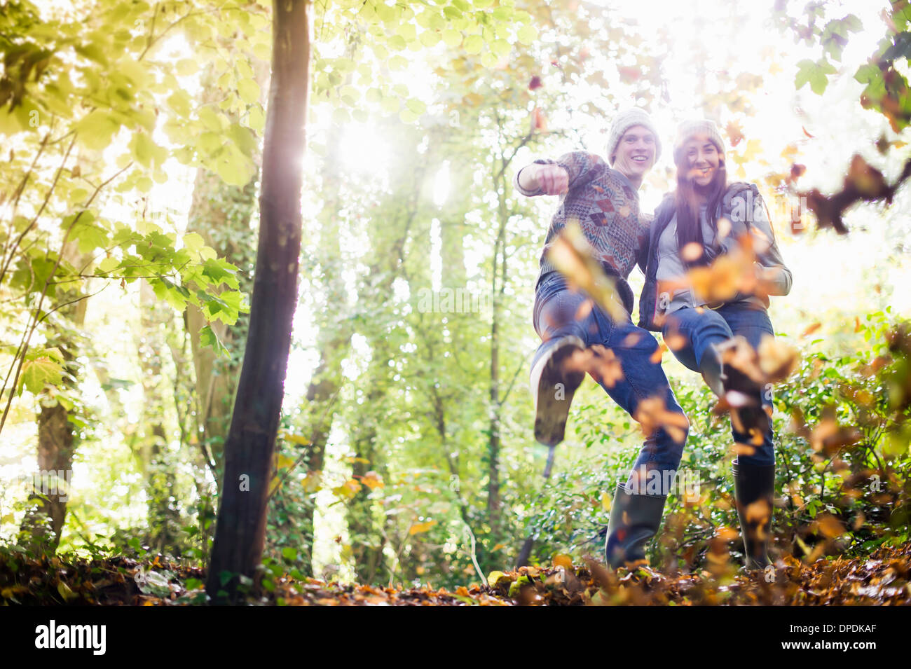Junges Paar mit Herbstlaub im Wald spielen Stockfoto
