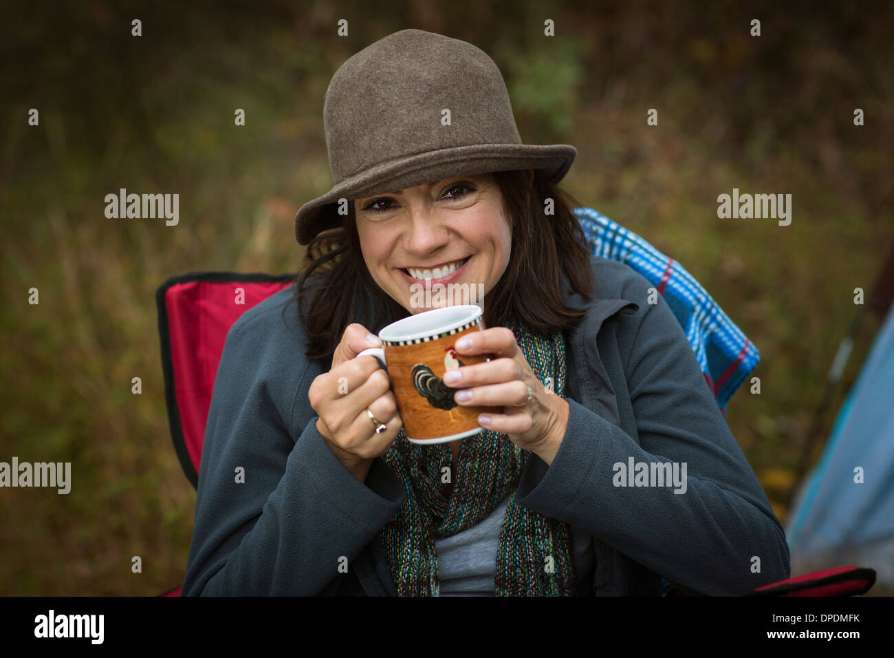 Reife Frau sitzen auf Campingstuhl, heißes Getränk trinken Stockfoto