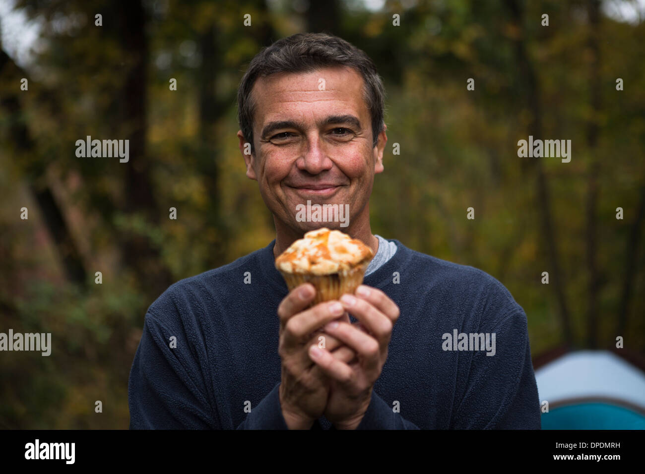 Reifer Mann im Wald hält cupcake Stockfoto