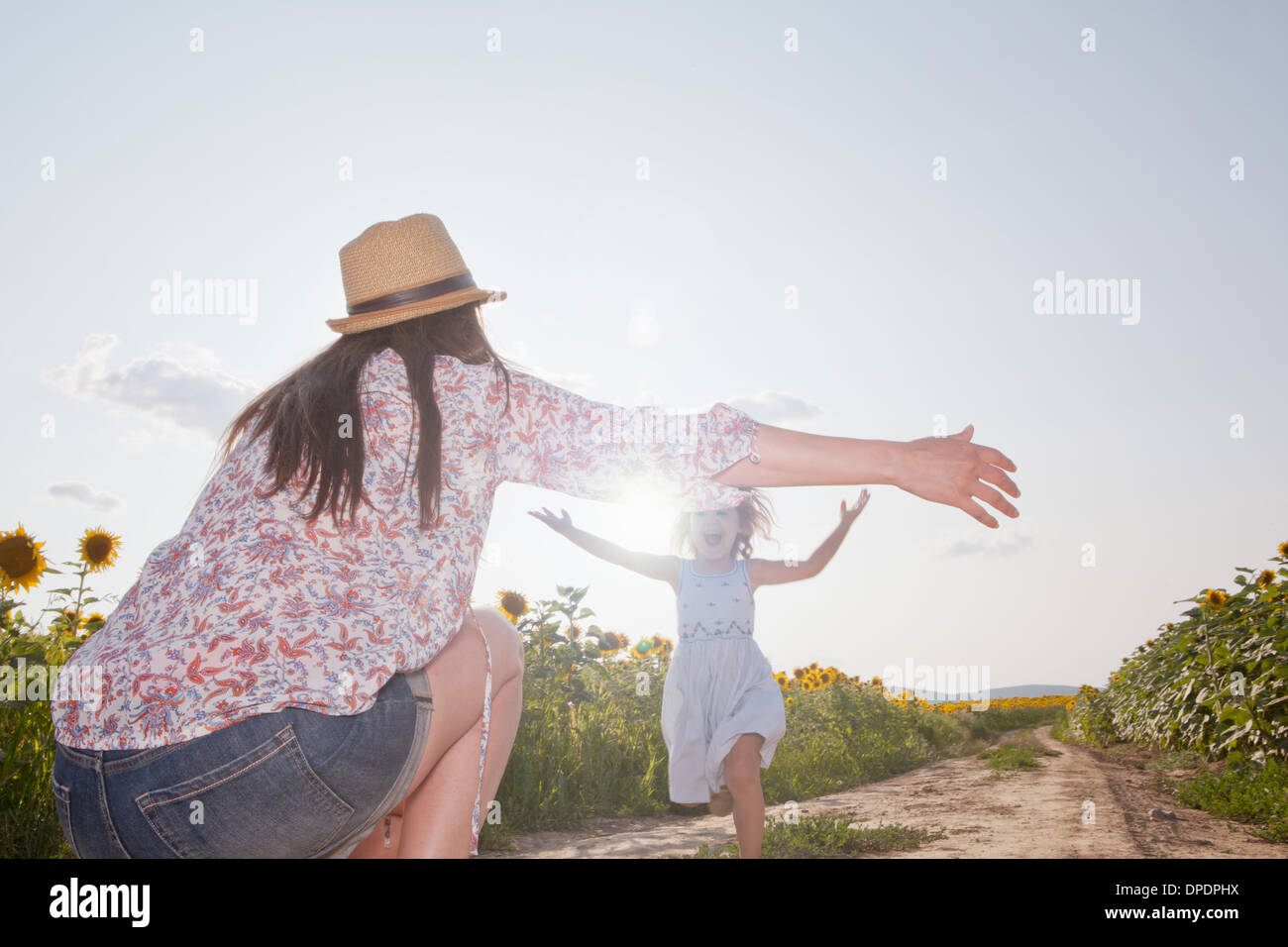 Mädchen läuft durch Feld, Mutter mit offenen Armen Stockfoto