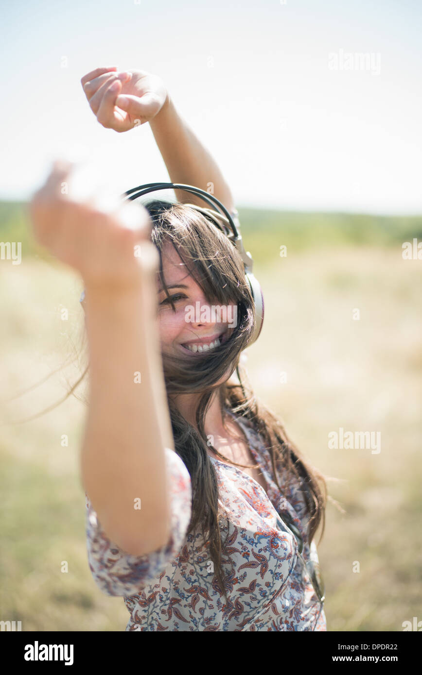 Porträt von Mitte erwachsenen Frau tanzt im Feld mit Arme heben, tragen von Kopfhörern Stockfoto