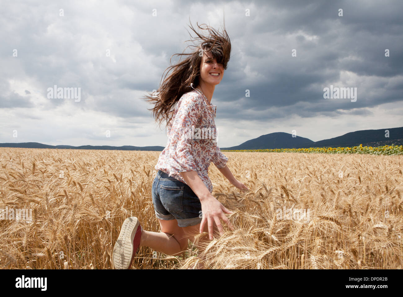 Mitte Erwachsene Frau läuft durch Weizenfeld Stockfoto