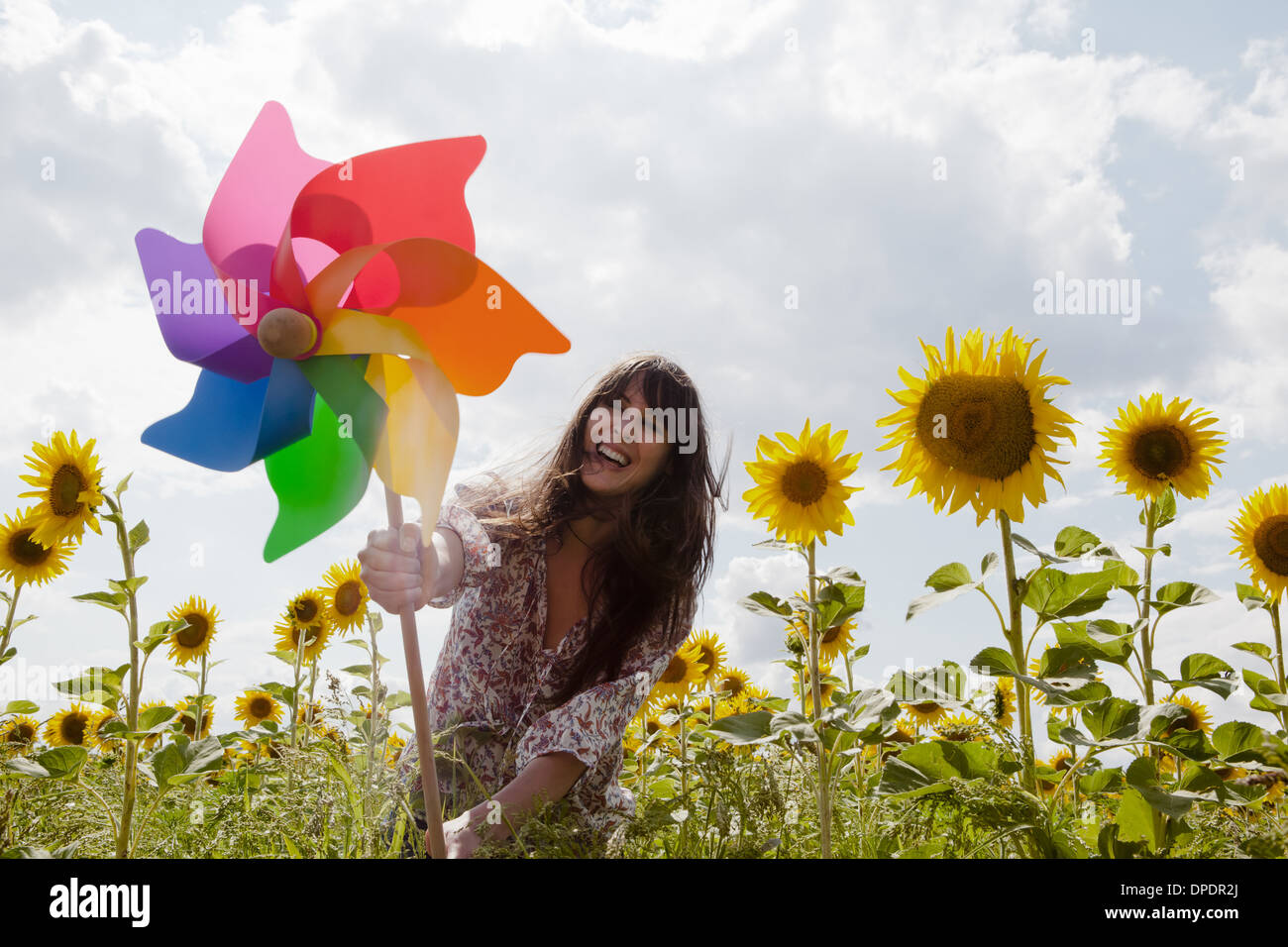 Frau Holding Windmühle im Feld von Sonnenblumen Stockfoto