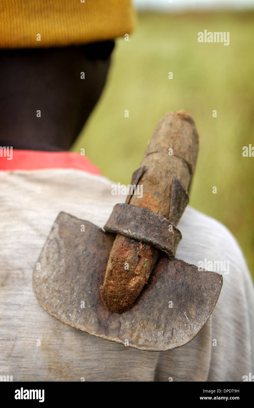 Ghanaischen Bauern zu Fuß zur Arbeit in den Bereichen mit einer traditionellen Mattock/Hacke über der Schulter Stockfoto