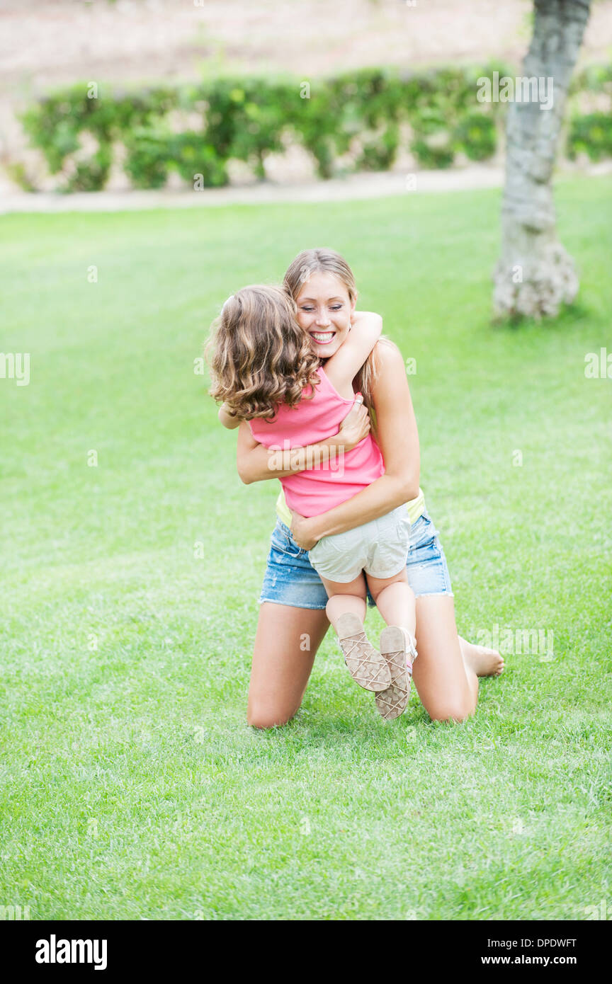 Mutter und Tochter umarmt auf Rasen Stockfoto