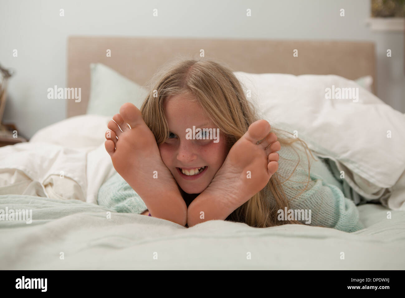 Porträt eines Mädchens auf Bett zwischen Füßen liegend Stockfoto