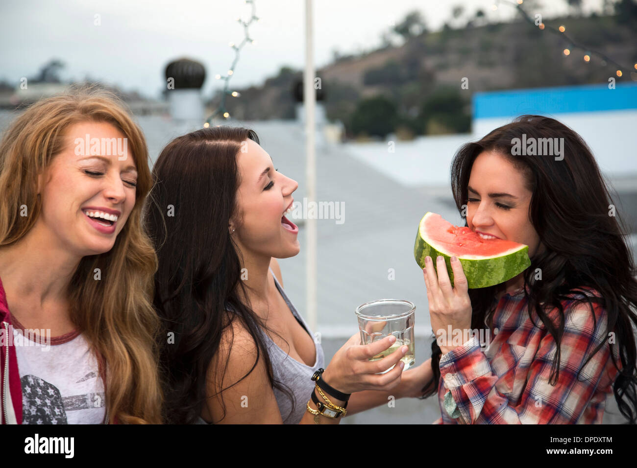 Drei junge Frauen am Grill mit großer Scheibe Melone Stockfoto