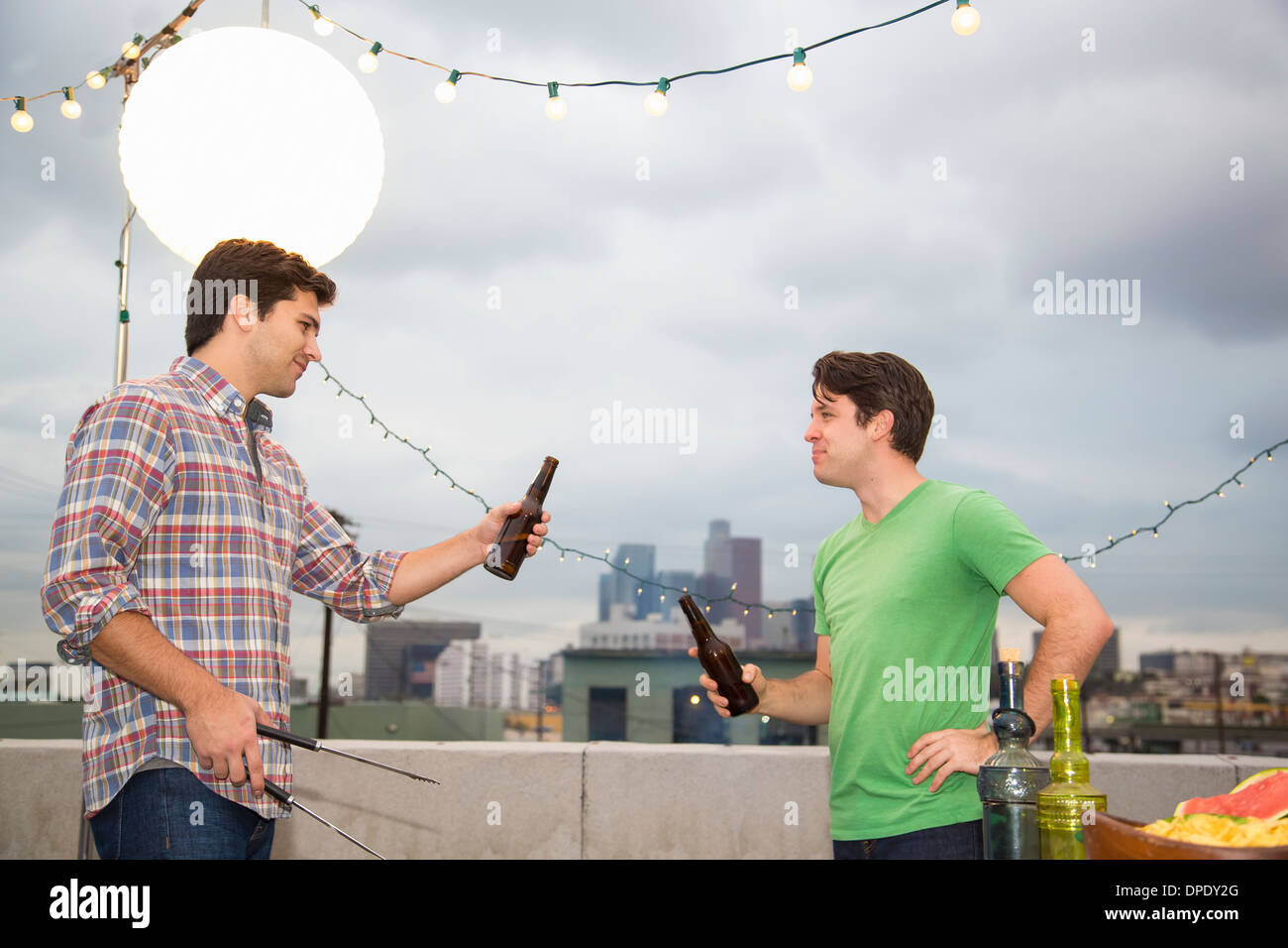 Zwei männliche Erwachsene Freunde im Chat bei Dach-barbecue Stockfoto