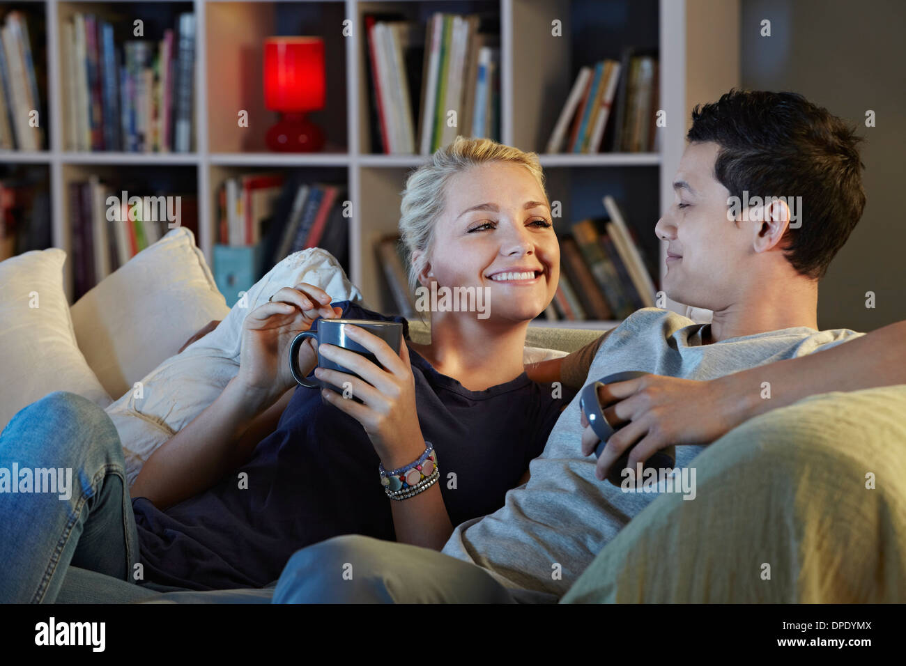 Junges Paar auf Sofa mit Heißgetränken Stockfoto