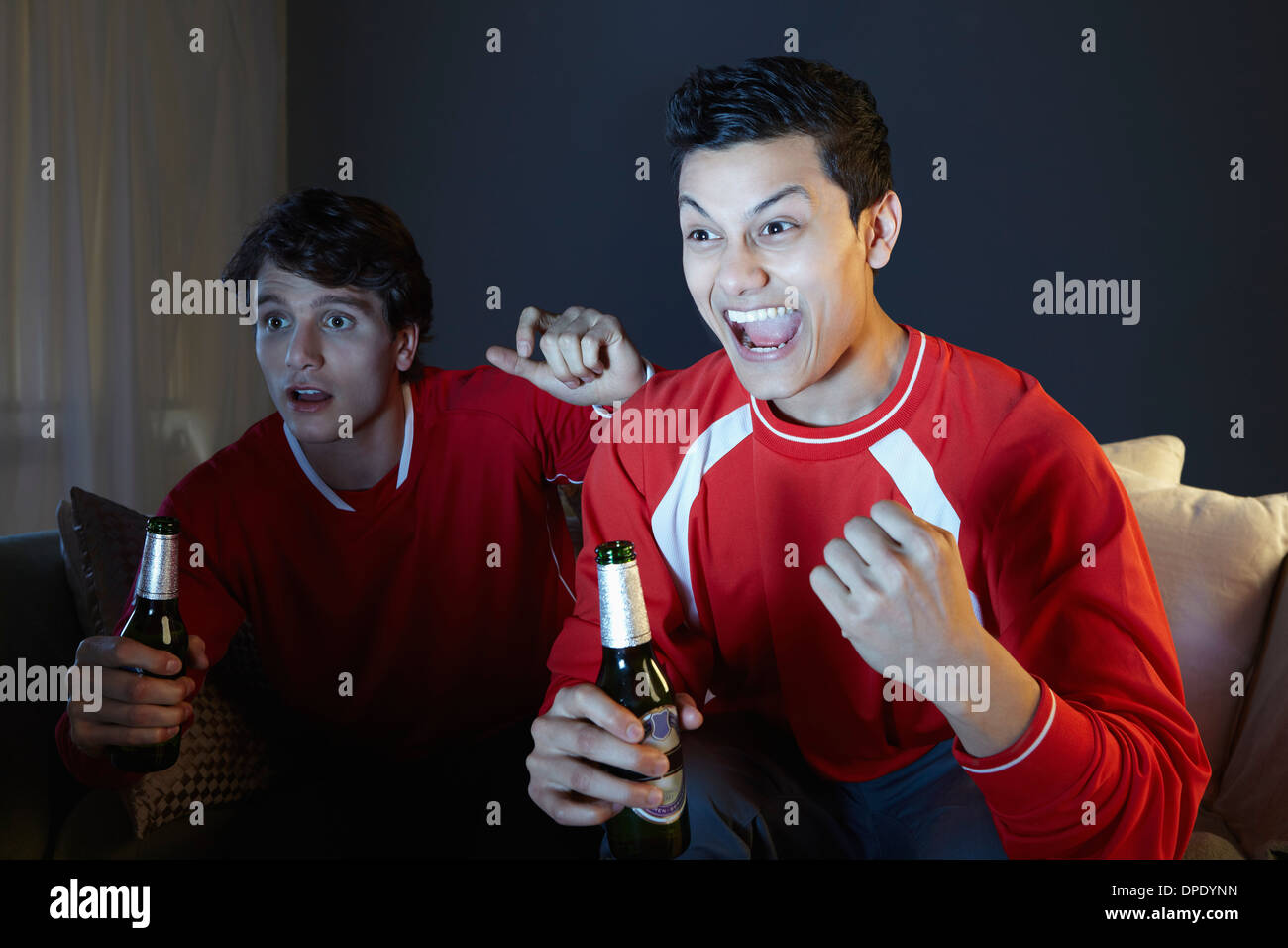 Junge Männer Sport im Fernsehen beobachten, halten Bierflasche Stockfoto