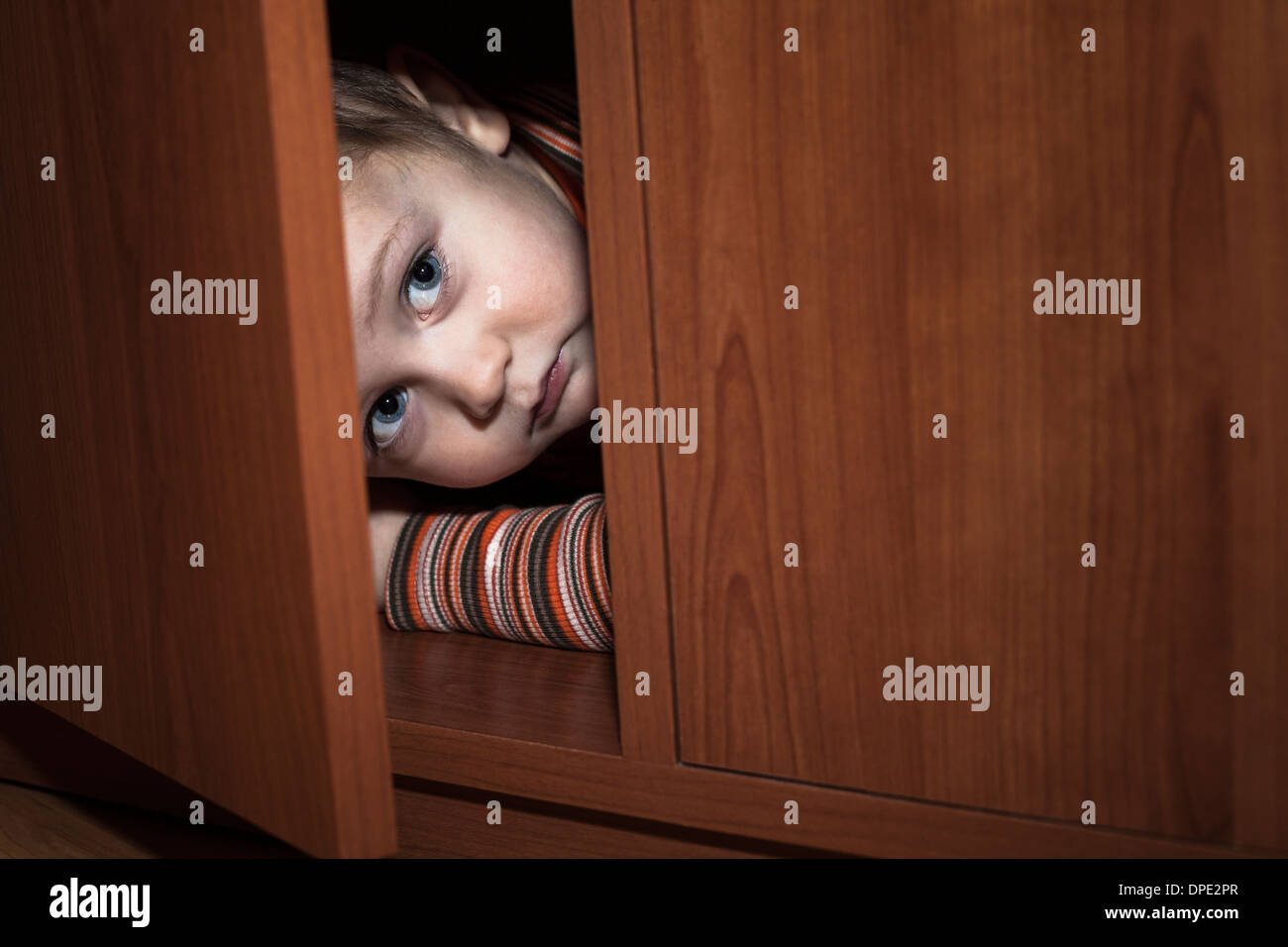 Angst Kind junge versteckt sich im Kleiderschrank Stockfoto