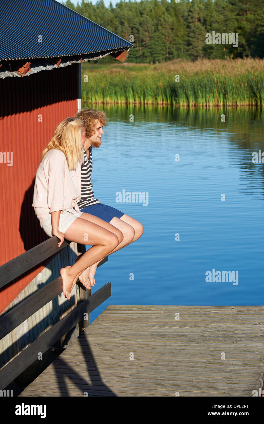 Junges Paar sitzt neben See, Hotels, Schweden Stockfoto